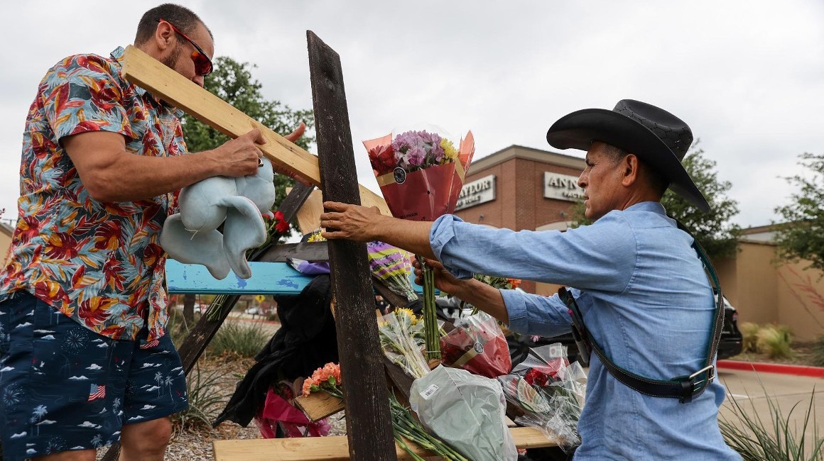 Ciudadanos comienzan a construir cruces para una vigilia en recuerdo de los que murieron en un tiroteo masivo en la entrada del Allen Premium Outlet Mall en Allen, Texas.