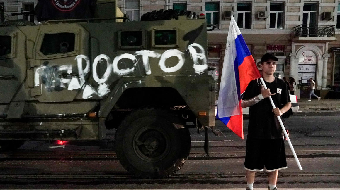 Un hombre sostiene una bandera rusa frente a un vehículo militar del grupo Wagner. 24 de junio de 2023