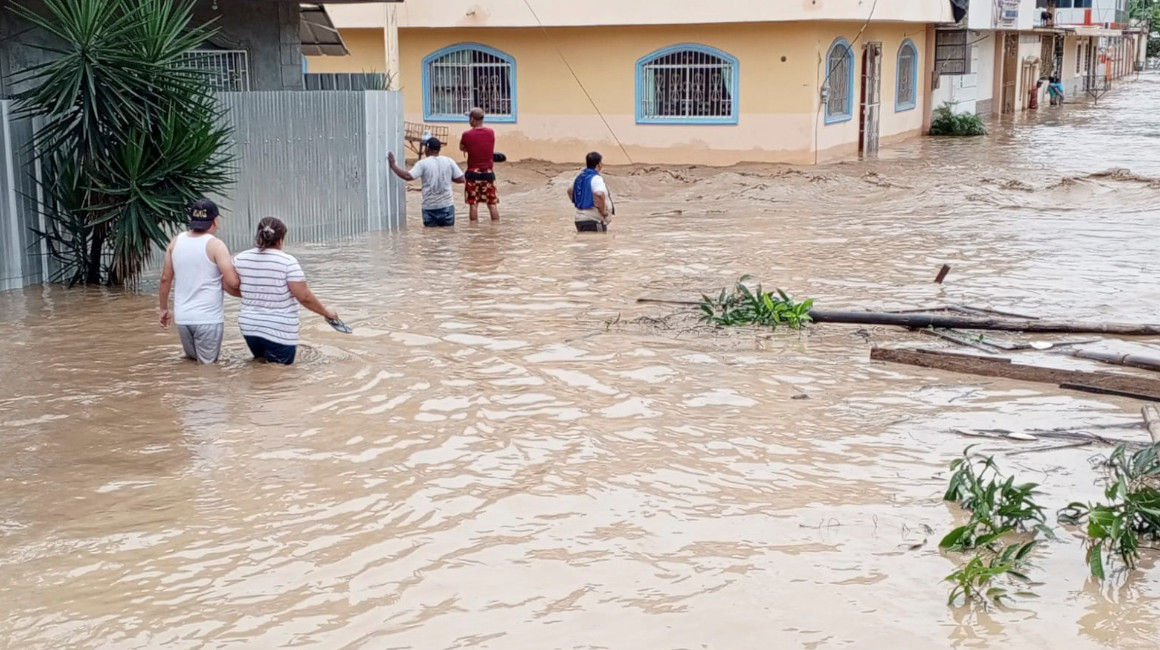 Imagen referencial. Varias personas caminan por una área inundada en Esmeraldas, en las pasadas lluvias, el 4 de junio de 2023. 