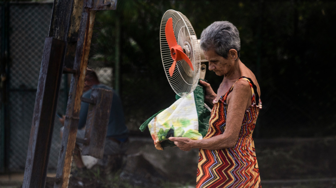 Una mujer carga una bolsa de alimentos y un ventilador, durante la ola de calor en Cuba, el 6 de julio de 2023. 