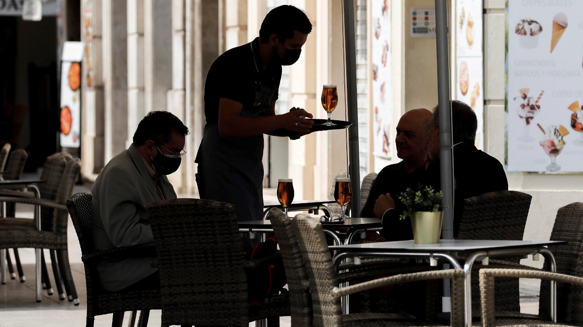 Un camarero atiende una mesa en un restaurante en Valencia, España.
