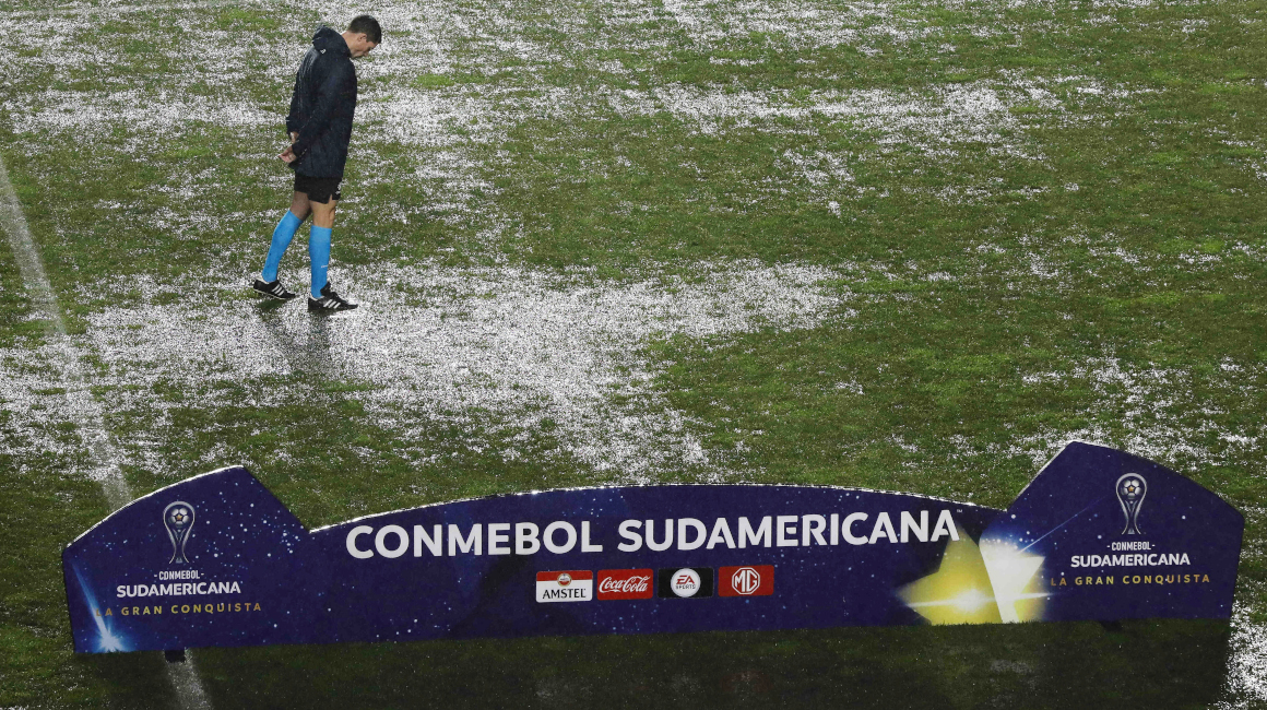 El árbitro argentino Facundo Tello inspecciona el campo inundado para el partido entre Audax Italiano y Ñublense en el estadio Ester Roa Rebolledo de Concepción, el 20 de julio de 2023.