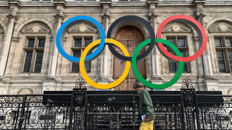 Un hombre pasa frente a los Anillos Olímpicos en el Hotel De Ville de París, el 2 de septiembre de 2022.