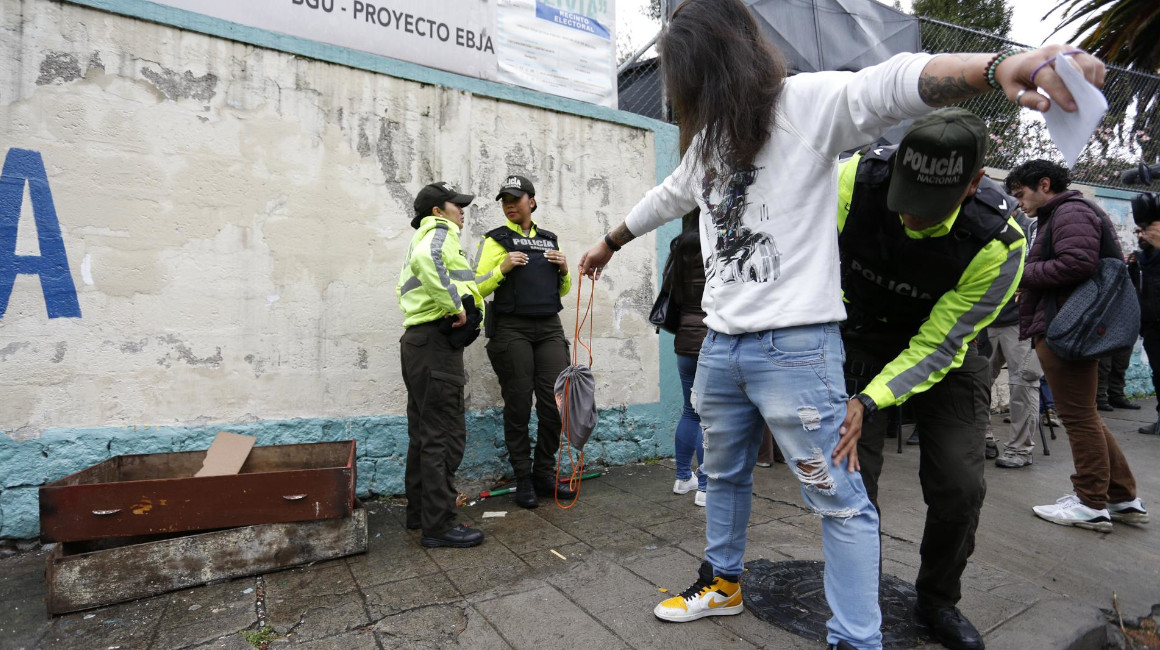 Un policía realiza una inspección a un hombre en un recinto electoral de Quito, el 20 de agosto de 2023. 