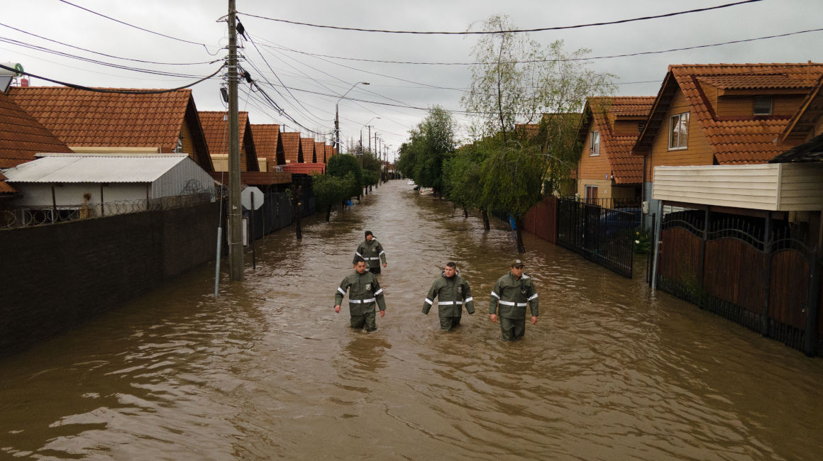 Rescatistas caminan por una calle inundada tras el desborde del río Claro, en la ciudad de Talca, en Chile, el 22 de agosto de 2023.