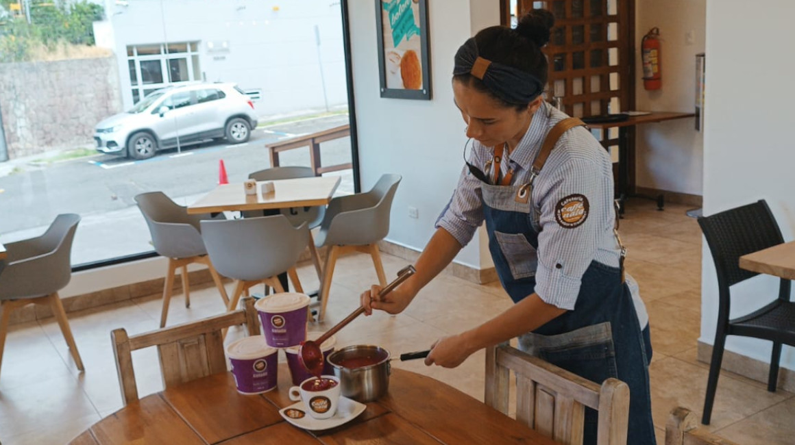 Una trabajadora de la cafetería Caffé & Nata, en el centro norte de Quito, sirve colada morada en una taza. Foto del 14 de septiembre de 2023.