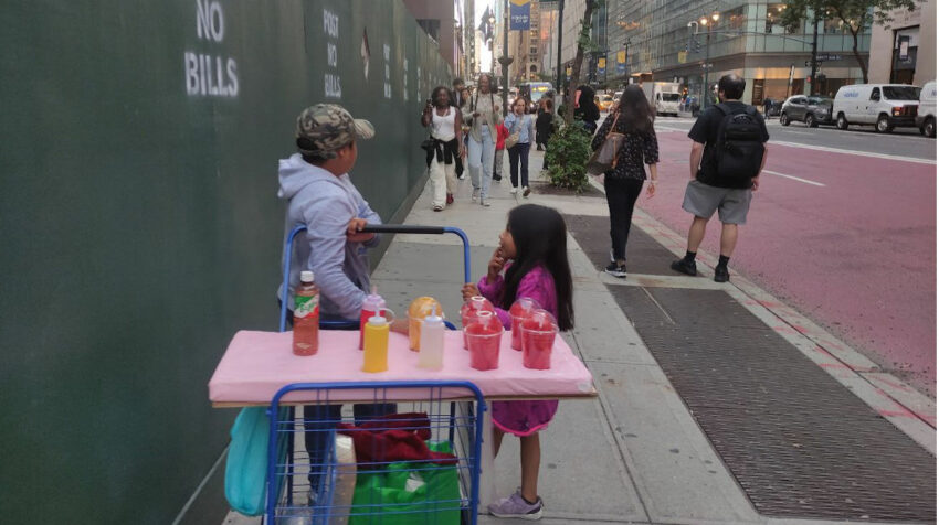Dos menores de edad ecuatorianos empujando una carretilla con fruta picada en el Downtown de Manhattan, en Nueva York.