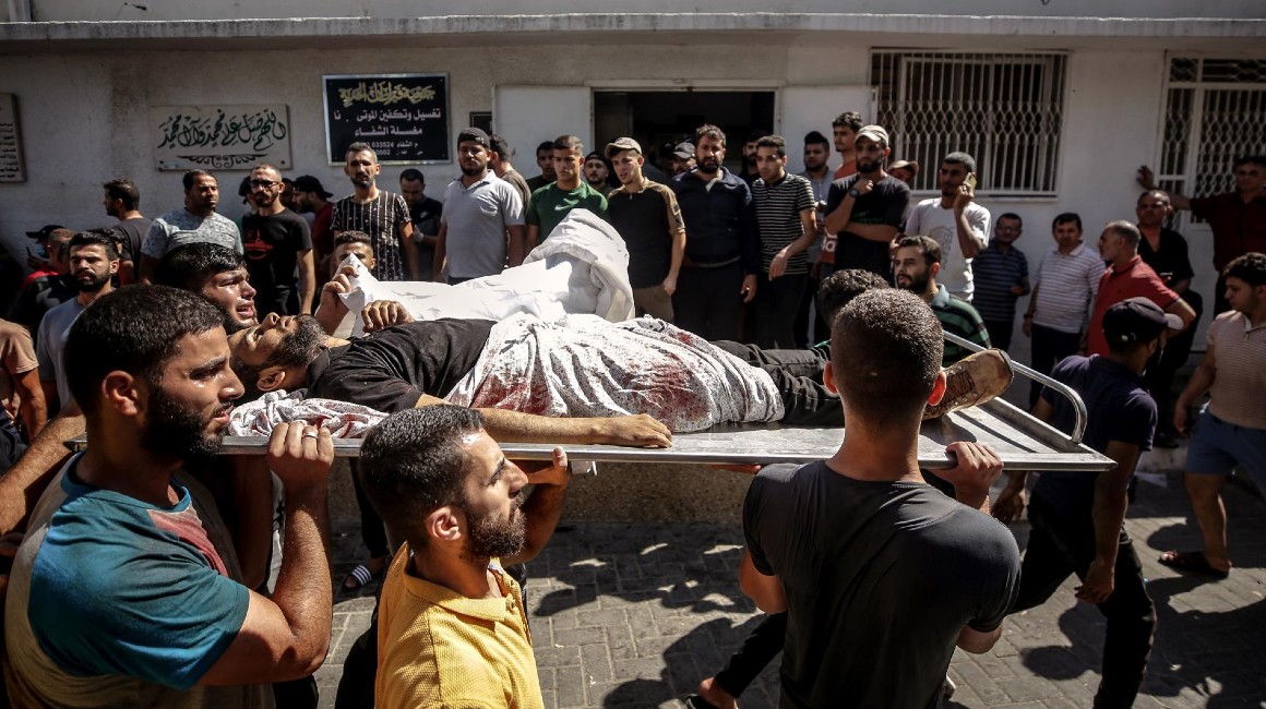 Ciudadanos palestinos portan el cuerpo de un combatiente muerto durante el asalto a los asentamientos de Israel.