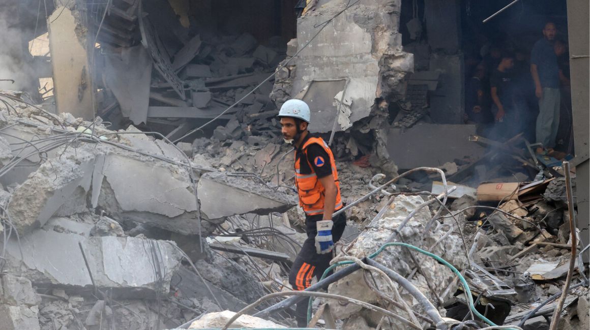 Un rescatista palestino se encuentra entre los escombros de un edificio destruido en el centro de la ciudad de Khan Yunis, fuertemente bombardeado en el sur de la Franja de Gaza, luego de un bombardeo israelí durante la noche, el 10 de octubre de 2023.