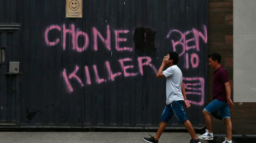 Dos hombres pasan junto a un grafiti alusivo a una de las bandas criminales en Durán, Guayas, azotado por la violencia, el 8 de octubre de 2023. 