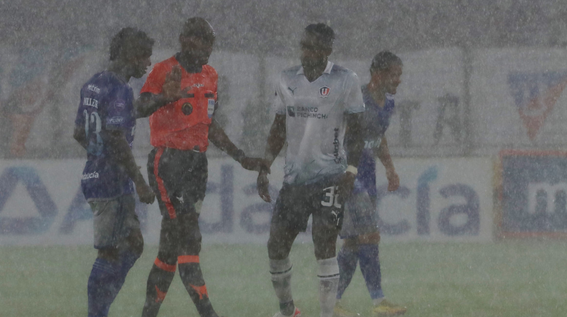 Los jugadores de Liga y Emelec, durante un partido con una fuerte lluvia, en Quito, el 22 de octubre de 2023.