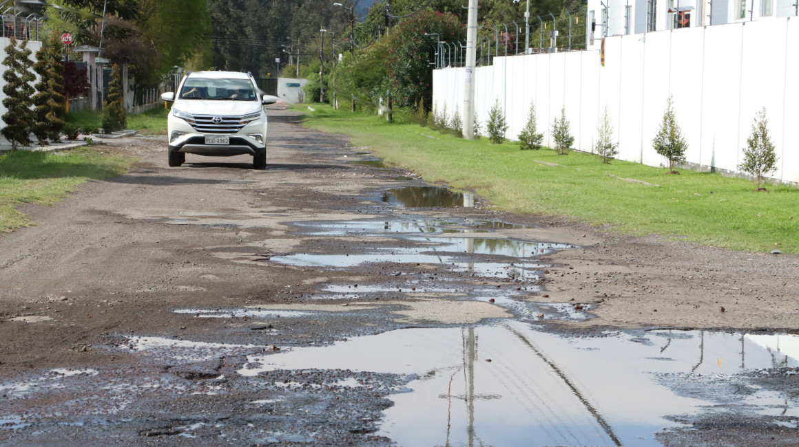 Un vehículo intenta circular por una vía llena de baches en Quito, el 22 de octubre de 2023.