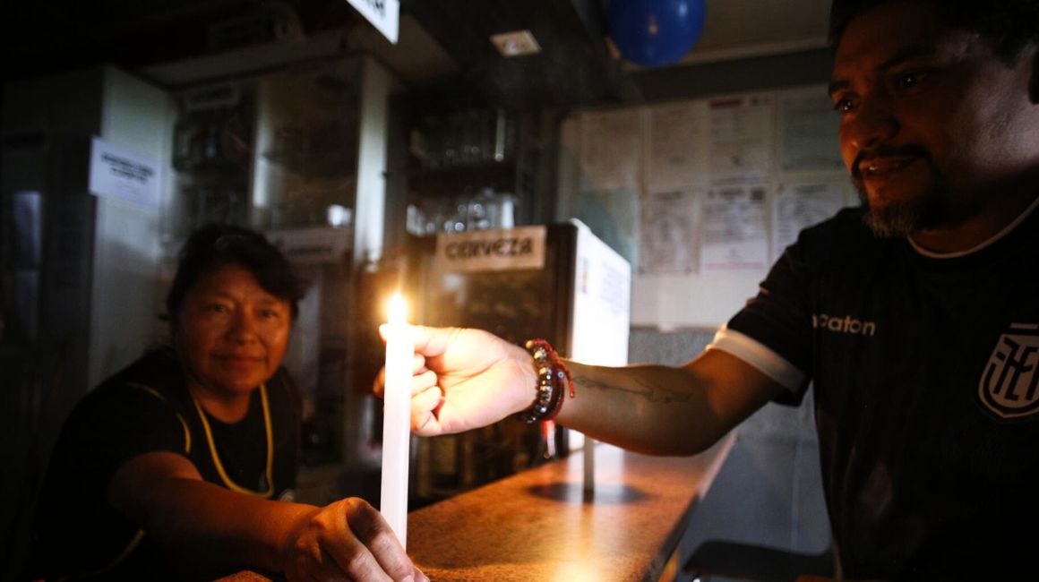 Un hombre enciende una vela en un bar por falta de energía en Quito el 28 de octubre de 2023.