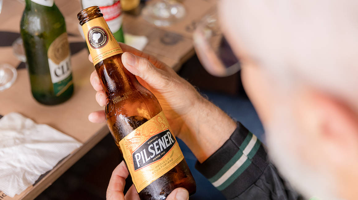 Una persona sostiene una cerveza Pilsener, marca de la empresa Cervecería Nacional, cuyo principal accionista es AB InBev.