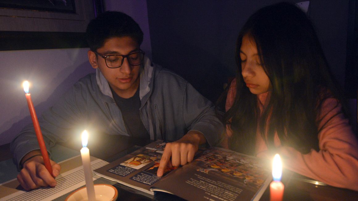 Renata y Daniel Barros estudiando con velas por el corte de energía eléctrica en Cuenca, el 27 de octubre de 2023.