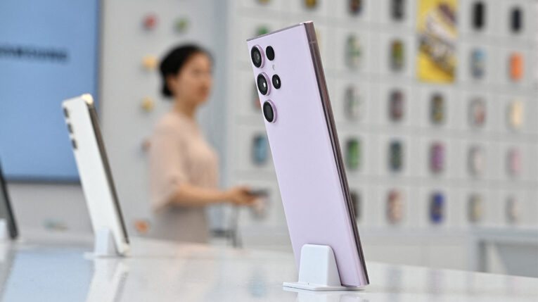 Una mujer pasa junto a un teléfono inteligente Samsung Galaxy S23 Ultra (derecha) en exhibición durante un evento de vista previa para los medios de comunicación de una nueva tienda insignia de Samsung Electronics en el distrito de Gangnam en Seúl el 28 de junio de 2023.