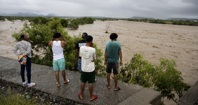 Personas observan el río Ocoa, que luce un inmenso caudal producto de las intensas lluvias.