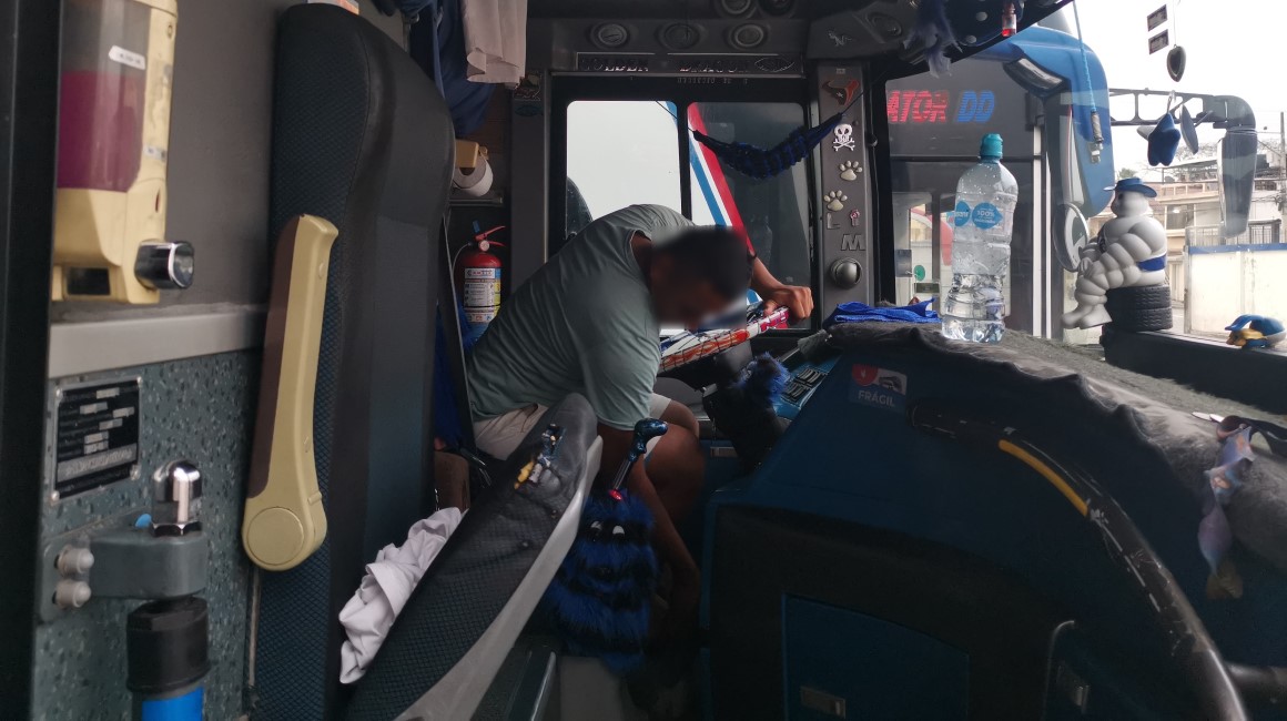 El conductor de un bus de transporte interprovincial limpia su cabina previo a un viaje, en un estacionamiento del norte de Guayaquil.