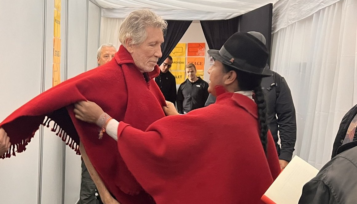El músico Roger Waters recibe un poncho por parte de Leonidas Iza.