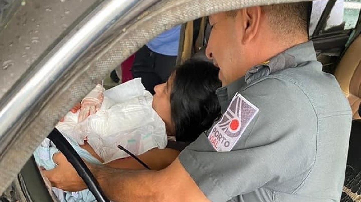 Imagen de una mujer dando a luz en el asiento de copiloto de un vehículo.