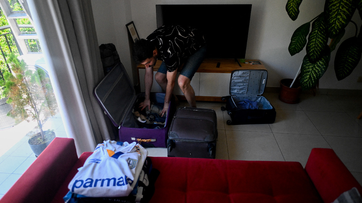 Un joven empaca para mudanza en Buenos Aires debido a crisis inmobiliaria.