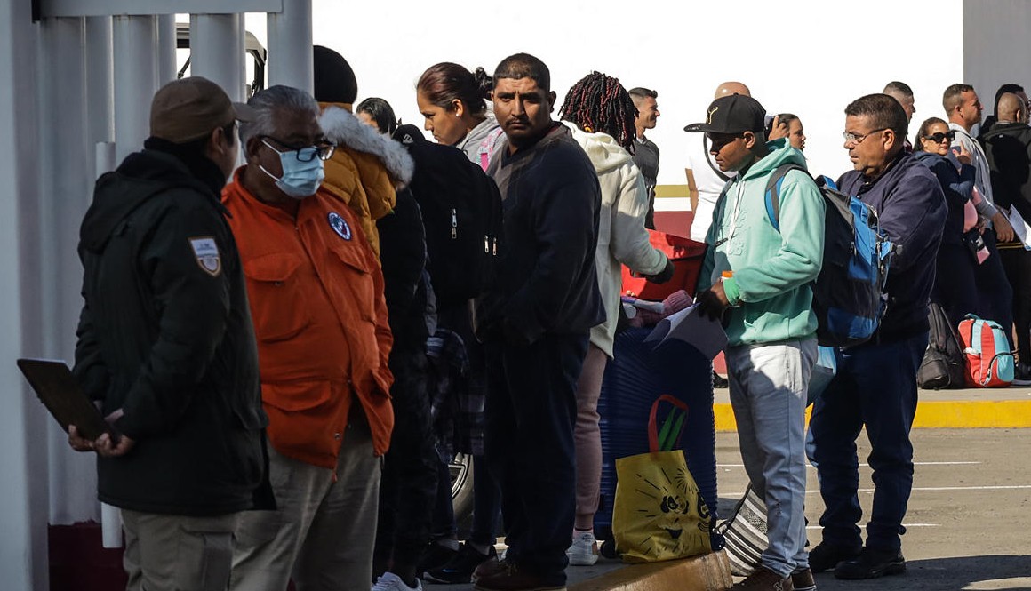 Migrantes hacen fila para cruzar la frontera de México y Estados Unidos en Tijuana.