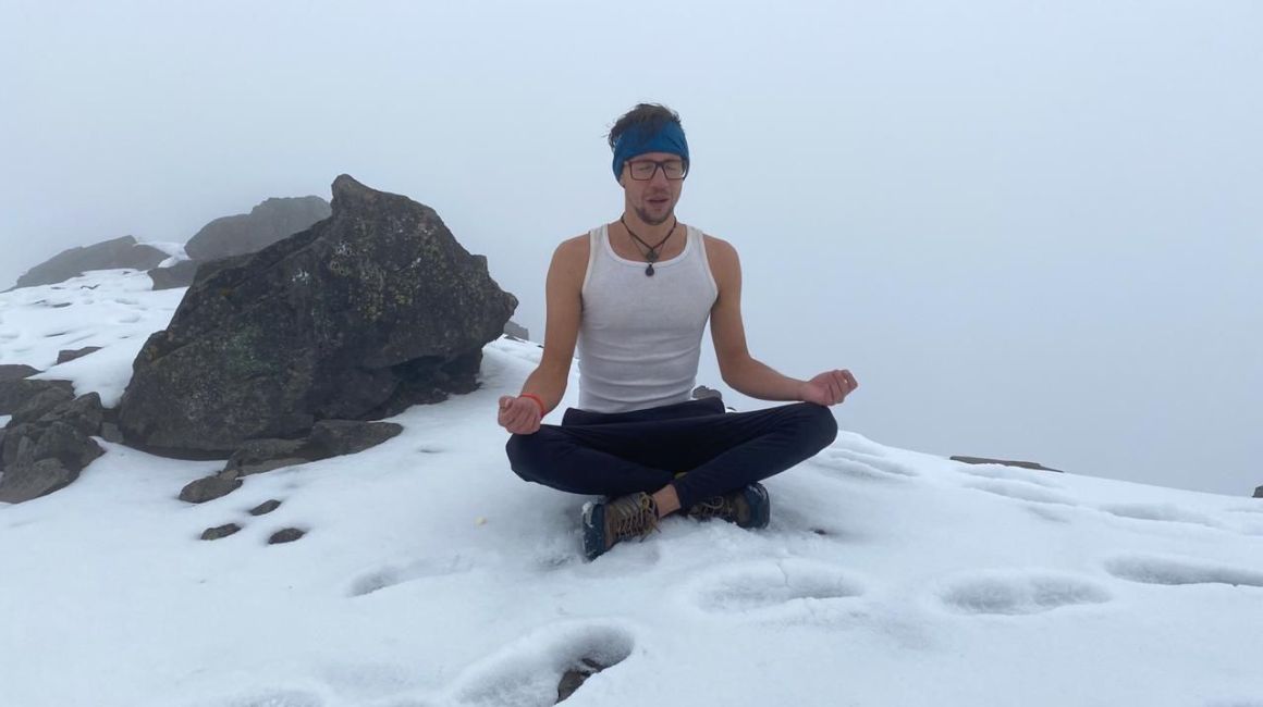 Juan Neira meditando en la montaña, con ropa ligera a bajas temperaturas. 