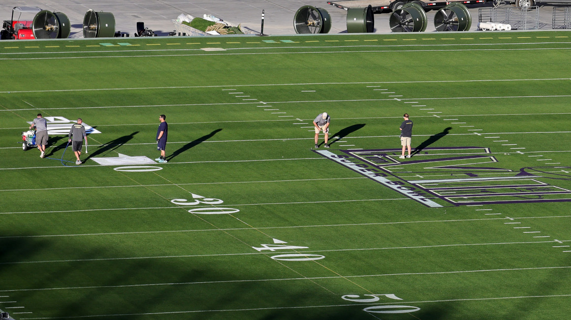 Los trabajadores pintan números y logotipos en el campo afuera del Allegiant Stadium,mientras los equipos se preparan para el Super Bowl LVIII.