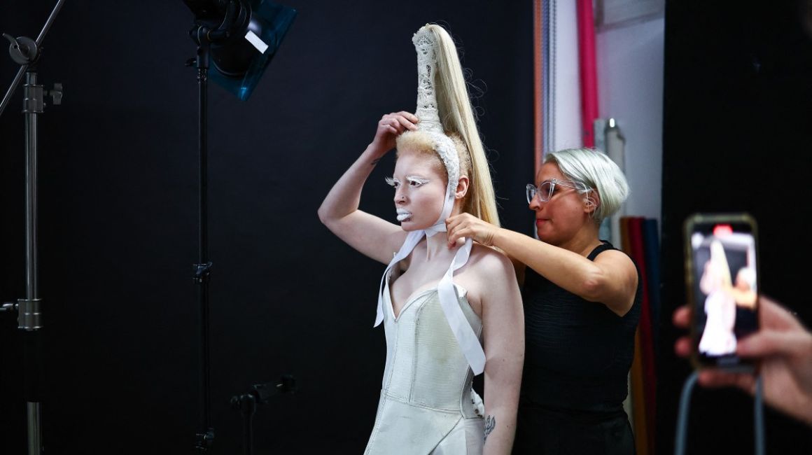 La diseñadora Syban Velardi-laufer ayuda a Nan M, modelo no binaria con albinismo, en la Semana de la Moda de Londres.