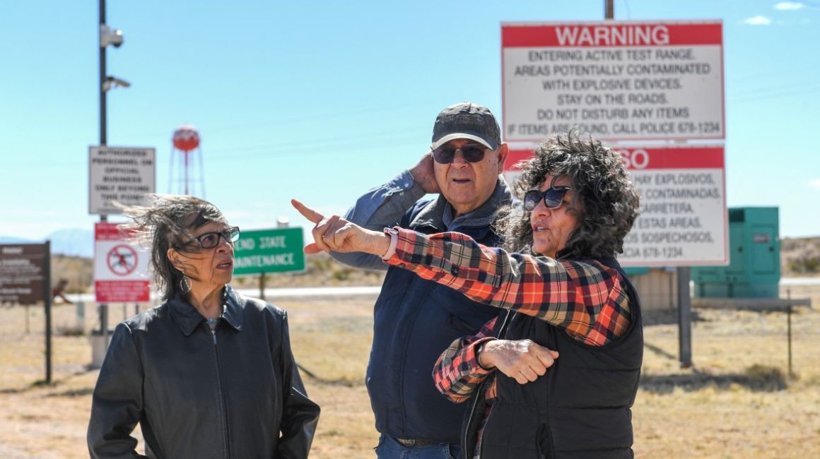 Louisa López (izq), Wesley Burris y Tina Cordova hablan frente a la entrada del campo de misiles White Sands, donde se encuentra el sitio 'Trinity', donde probaron la bomba atómica.