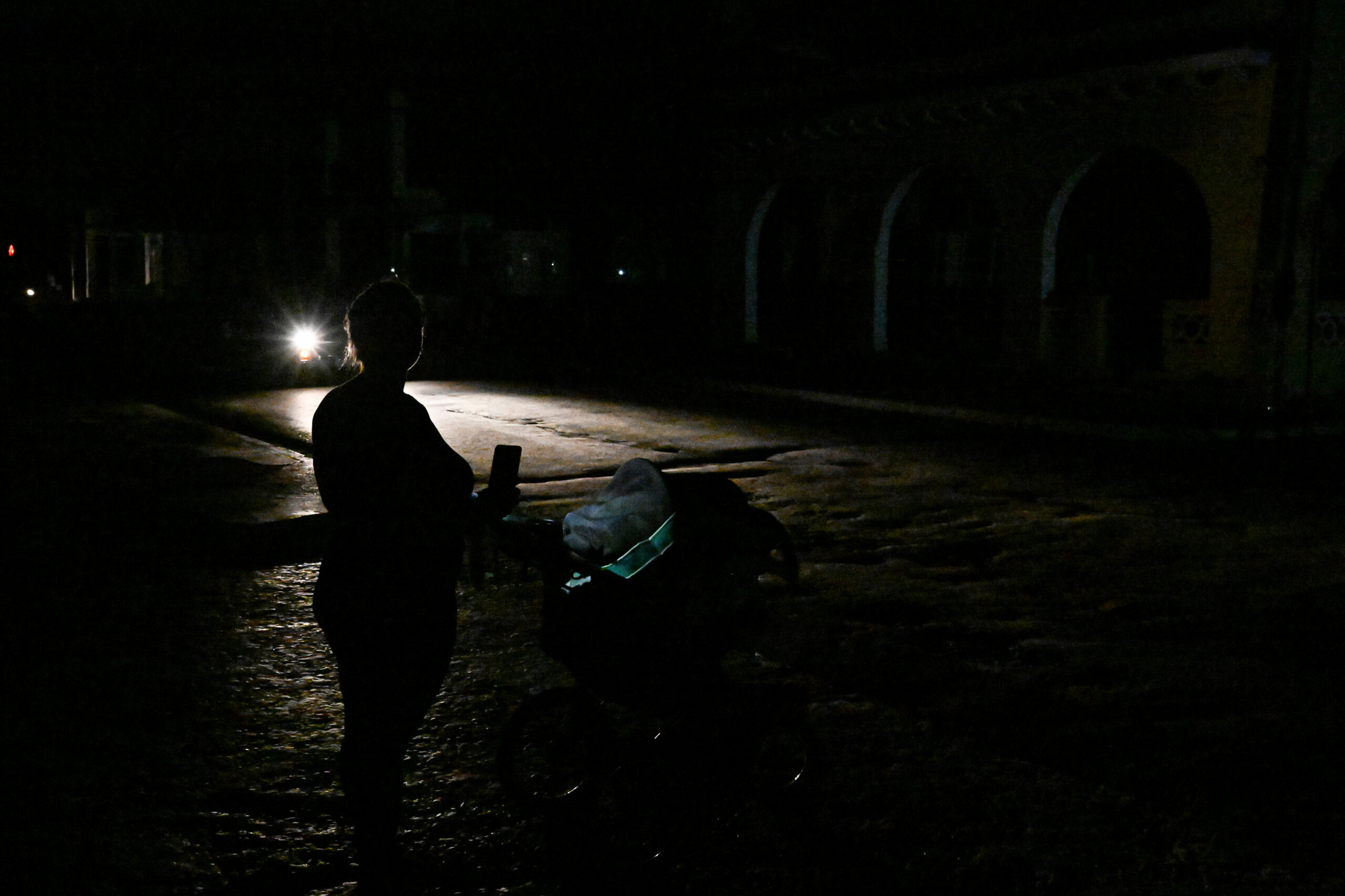 Una mujer empuja un cochecito por una calle oscura durante un apagón en Bauta, provincia de Artemisa, Cuba.
