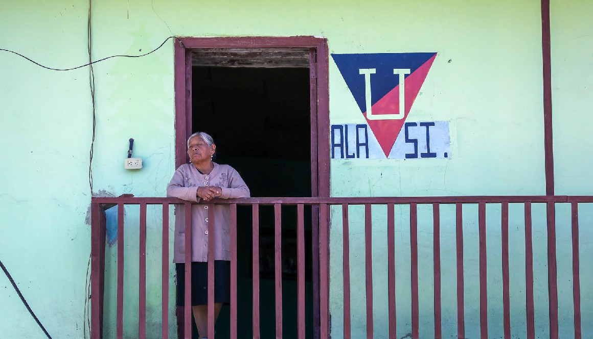 Una mujer se asoma por un balcón en la población de Alausí.