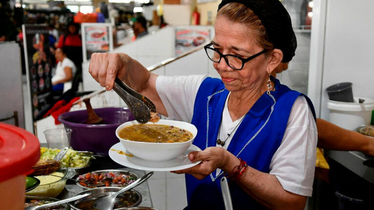 Comerciante sirve un plato de fanesca en un mercado de Guayaquil, el 26 de marzo de 2024.