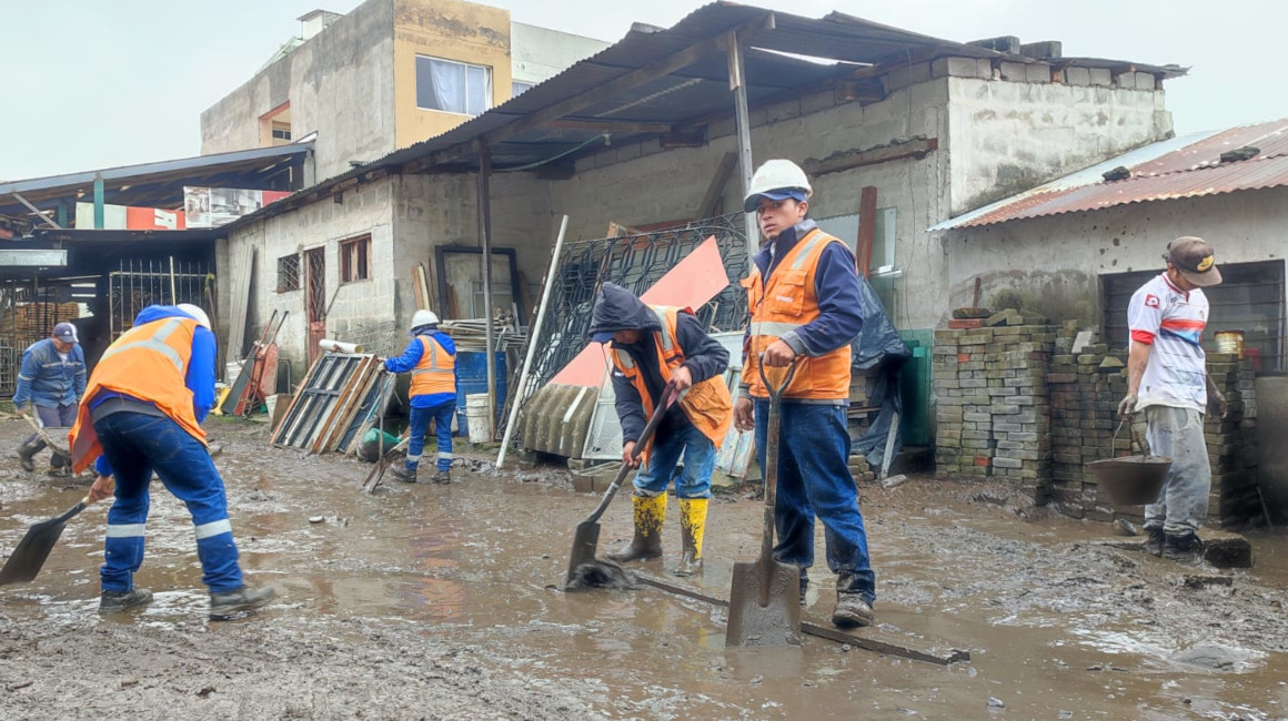 Funcionarios del Municipio de Quito y moradores de La Gasca limpian el patio de una vivienda afectada, el 3 de abril de 2024.