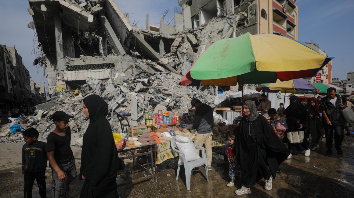 Palestinos caminan entre los escombros de un edificio de Gaza destruido por Israel.