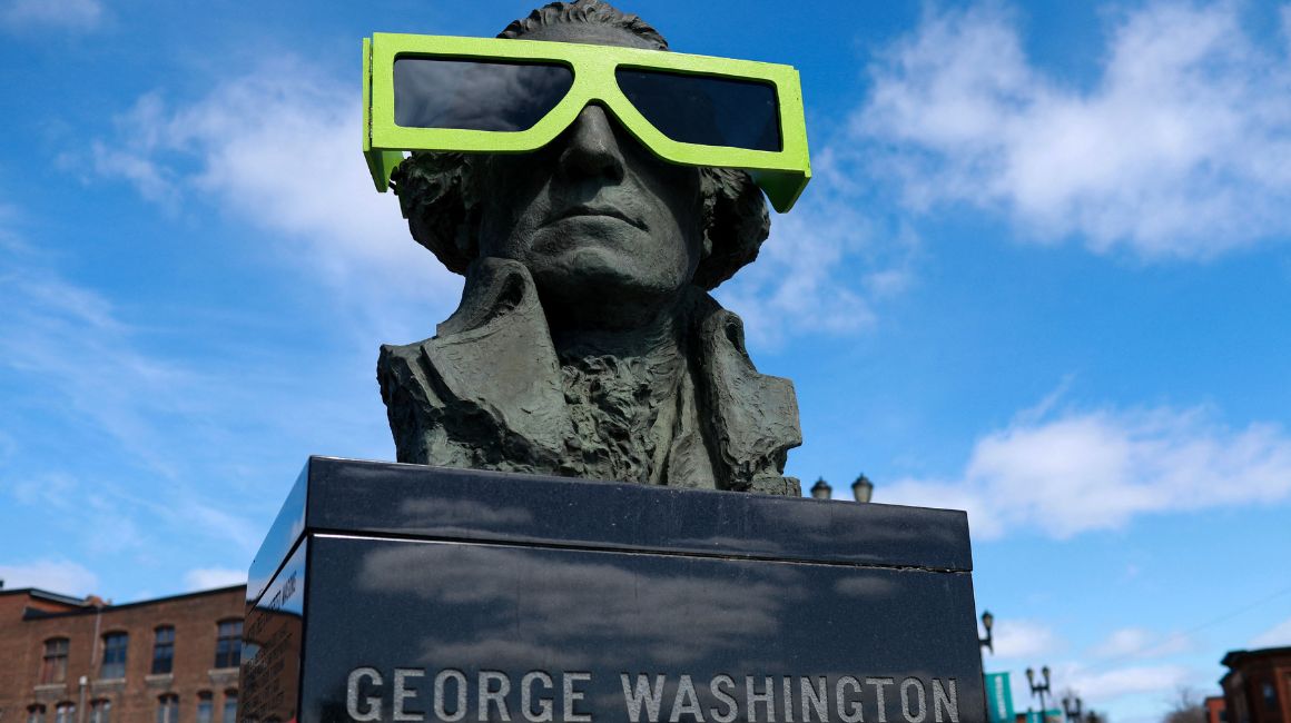Una estatua de George Washington usa gafas que simulan las usadas para ver el eclipse solar total de este 8 de abril, en Houlton, Maine. 