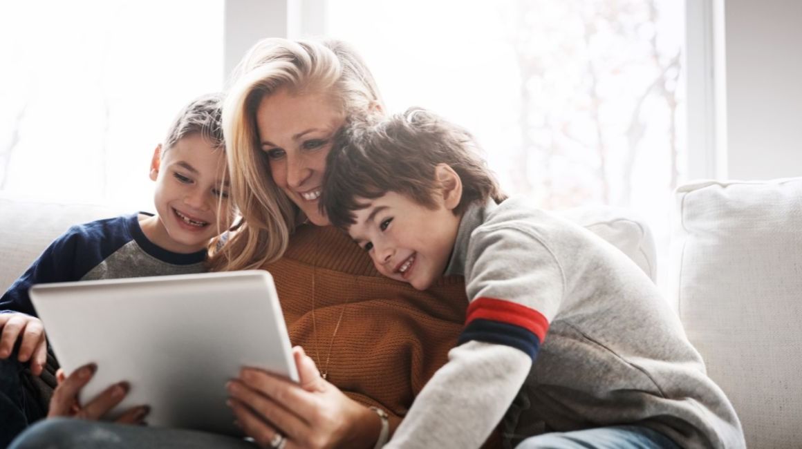 mama sentada en un sillon mirando una tablet con sus hijos