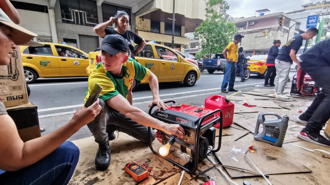 Un dependiente prende y prueba un generador eléctrico portátil en las calles Rumichaca y Aguirre, en el centro de Guayaquil, mientras le explica el funcionamiento a una compradora.