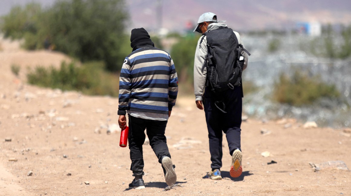 Los migrantes ecuatorianos Luis Hernández Saldaña (L, 40) y Javier Villareal (45) caminan por las orillas del Río Bravo en busca de una brecha para cruzar a Estados Unidos desde Ciudad Juárez, en México.