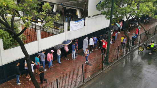 Varias personas esperan bajo la lluvia en Guayaquil, durante la consulta popular, el 21 de abril de 2024.
