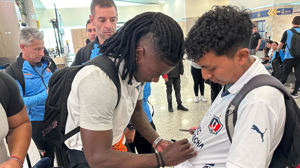 El jugador de Liga de Quito, Ricardo Adé, le firma la camiseta a un hincha de la 'U' en el Aeropuerto Mariscal Sucre, el 22 de abril de 2024.