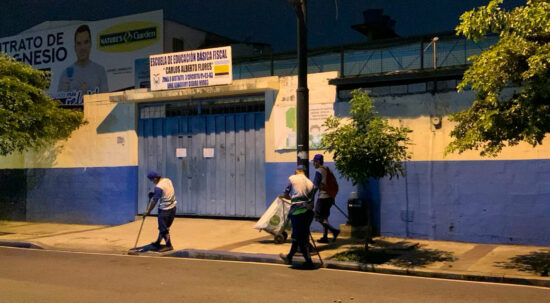 Personal de limpieza barre los exteriores de los recintos electorales en Guayaquil.