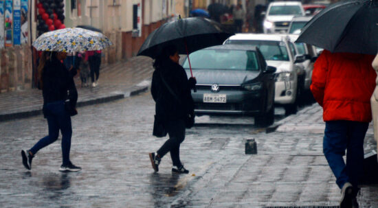 Ciudadanos en Cuenca se protegen de la lluvia con paraguas.