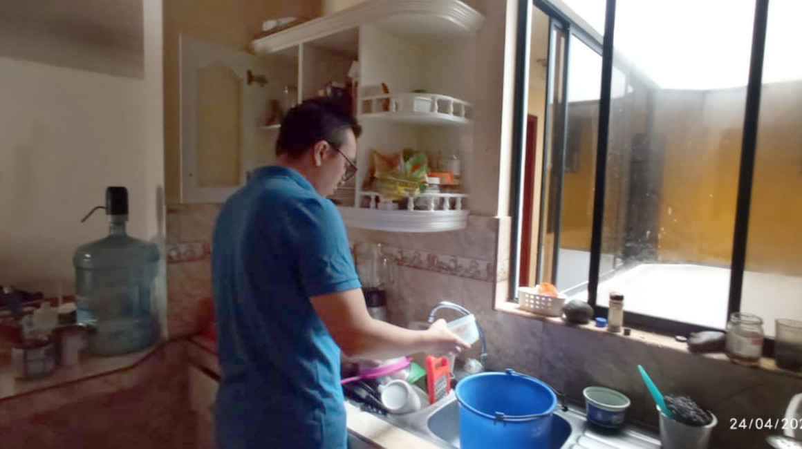 Andrés Valencia intenta lavar los platos de su casa, el 24 de abril de 2024 en Quito.