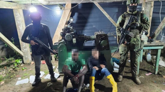 Militares junto a los dos detenidos en la fábrica de billetes falsos en Quinindé, Esmeraldas, el 26 de abril de 2024.
