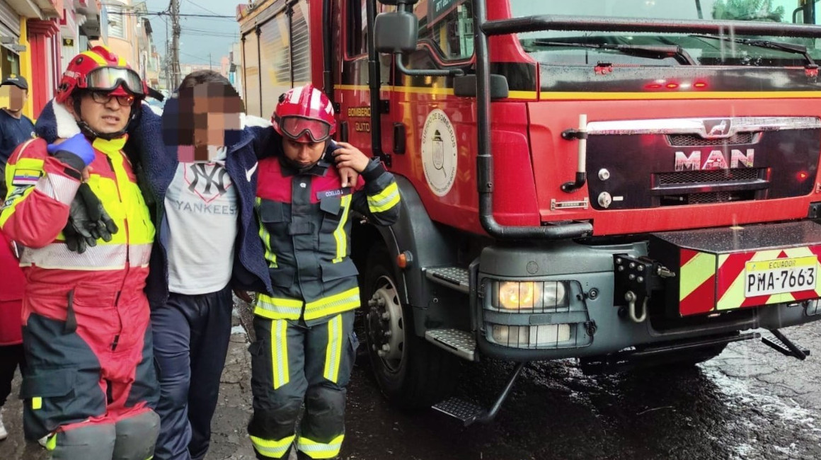 Dos bomberos ayudan a una persona afectada por la caída de un rayo, el 11 de mayo de 2024 en Quito.
