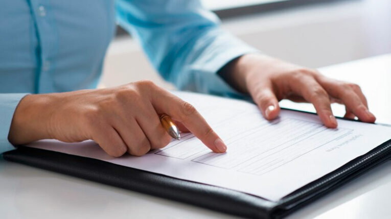Imagen referencial de una persona firmando un documento.