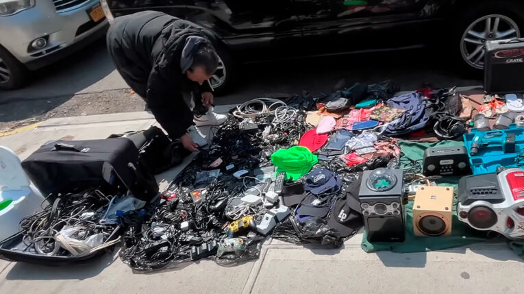 Migrante vende productos usados en una calle de Nueva York.