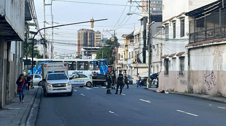 Policías y el camión de Criminalística junto al cuerpo de un hombre hallado en el centro de Guayaquil, el 21 de mayo de 2024.