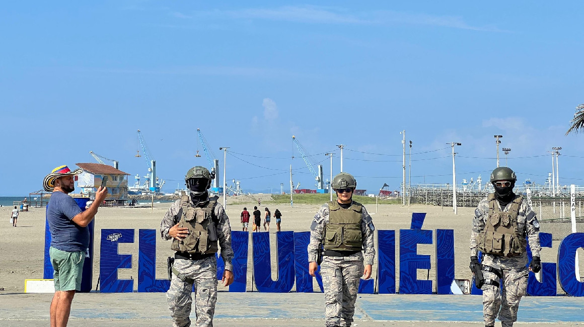 Un turista toma una fotografía a militares que vigilan la playa el Murciélago, en Manta, el 30 de marzo de 2024.